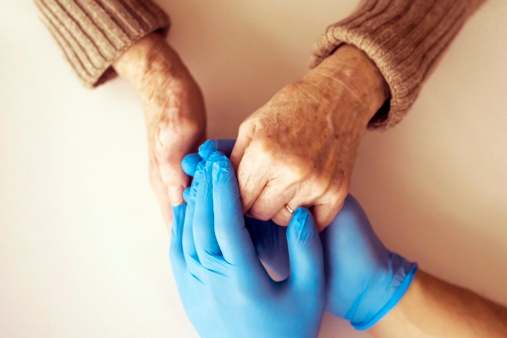 Care home visitor and resident holding hands