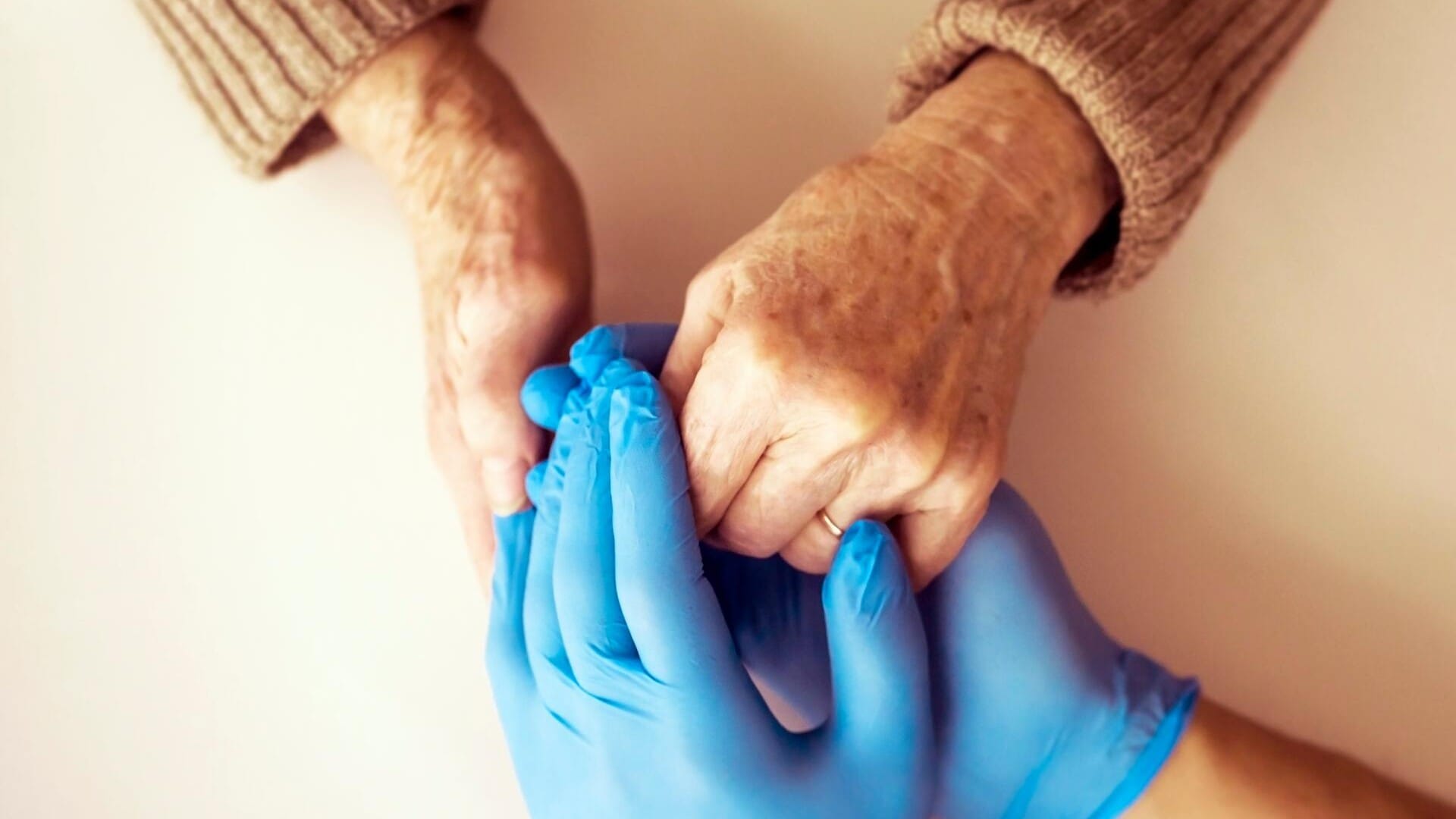 Care home visitor and resident holding hands